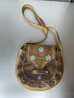 a brown purse with flowers painted on it sitting on top of a metal countertop