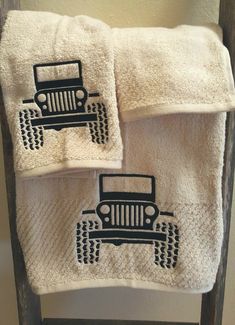 two white towels with black jeeps on them are sitting on a chair in front of a wall