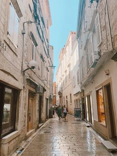 people are walking down an alleyway between two buildings