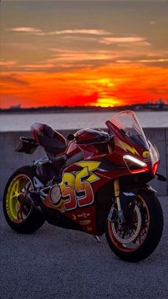 a red and yellow motorcycle parked in front of a sunset