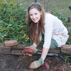 a woman kneeling down in the dirt with gardening gloves on