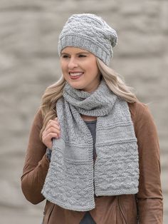 a woman wearing a gray knitted hat and scarf with a brown leather jacket on