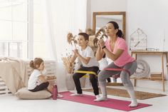 a woman and two children doing exercises in the living room with their mother watching them