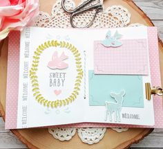 a close up of an open book on a wooden table with flowers and crafting supplies