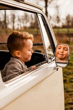 a young boy sitting in the drivers seat of a white truck looking at his reflection