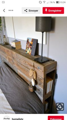 a bed with a wooden head board and books on it, next to a lamp