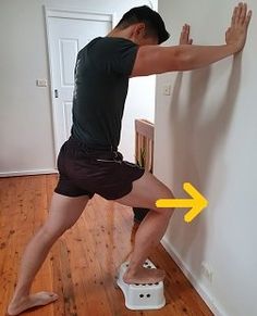 a man standing on a step stool in front of a wall with an arrow pointing to it