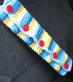 a crocheted headband with red and blue buttons on the end, in front of a car seat