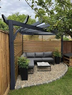 an outdoor seating area in the middle of a yard with wooden fence and plants on it