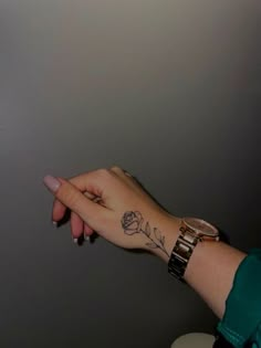 a woman's hand with a rose tattoo on it and a watch around her wrist