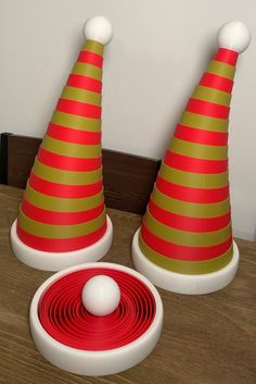 two red and green striped cone hats sitting on top of a wooden table next to a white ball