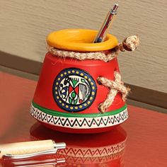 a pen holder with an orange lid and rope wrapped around it on a red table