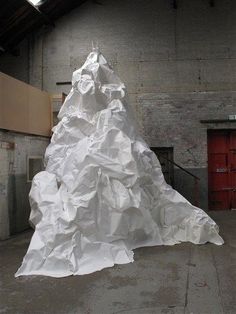 a large white piece of paper sitting on top of a cement floor next to a red door