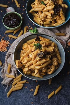 two bowls filled with pasta and sauce on top of a table