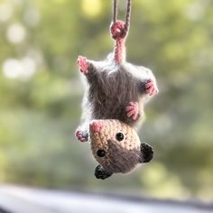 two stuffed animals hanging from strings in front of a window