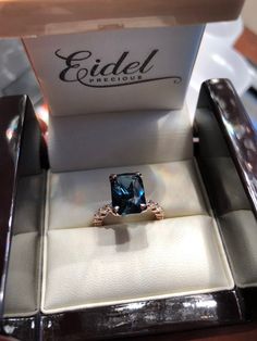 an engagement ring with a blue stone sits in a box on top of a table