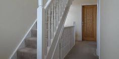 a white staircase leading up to the second floor in a home with carpeted stairs