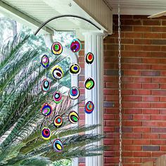 a colorful wind chime hanging from the side of a brick building next to a palm tree