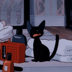 a black cat sitting on top of a window sill next to an orange radio