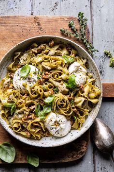 a bowl filled with pasta and meat on top of a wooden cutting board