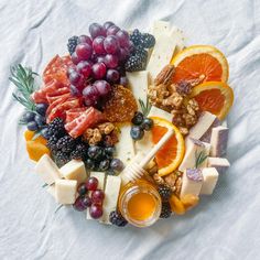 an assortment of cheeses, fruits and honey on a plate