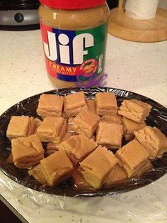 peanut butter and sugar cubes on a plate next to a jar of peanut butter