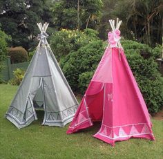 two teepees sitting in the grass next to each other