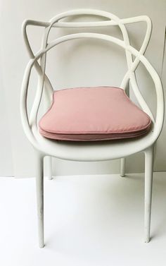 a white chair with a pink cushion on it