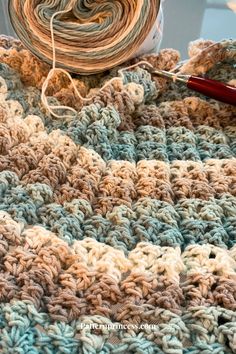 a crocheted blanket with yarn next to it