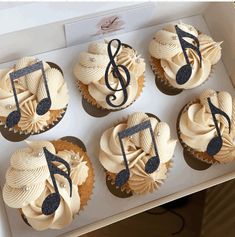 cupcakes decorated with music notes and musical symbols are displayed in a white box