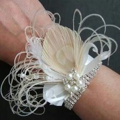 a close up of a person's arm wearing a bracelet with pearls and feathers