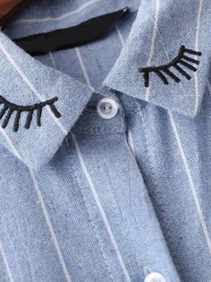 a blue shirt with black eyelashes on the front and back buttons, which have been embroidered onto it