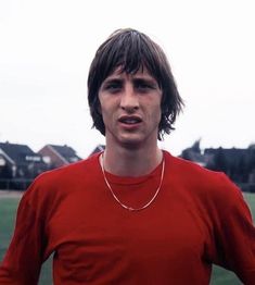 a young man in a red shirt standing on a soccer field