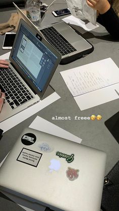 two people sitting at a table with laptops and papers in front of them that say almost free