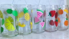 there are many glasses that have different designs on the glass and one is decorated with fruit