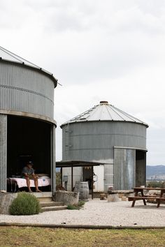 a man sitting on a bench in front of two silos next to each other