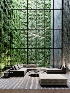 a living room filled with lots of furniture and green plants on the wall behind it