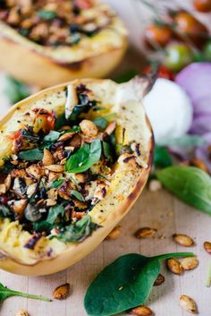 two stuffed acorns with spinach and nuts on a wooden table next to flowers