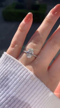 a woman's hand with a diamond ring on top of her finger and the other hand