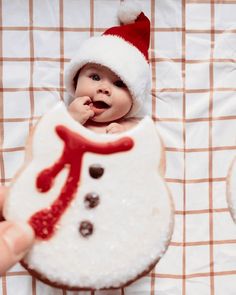 a baby wearing a santa hat is in a snowman cookie