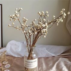 a vase filled with white flowers on top of a bed