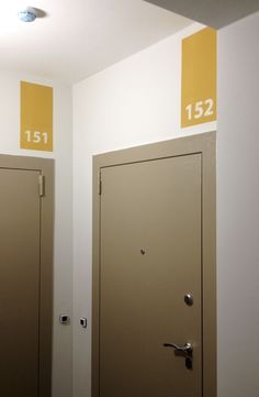 there are two doors with numbers on them in the room that is painted yellow and white