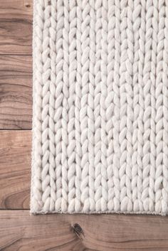 a white rug on top of a wooden floor next to a wood flooring board