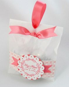 a small white bag with a pink ribbon on it