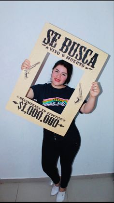 a woman in black shirt holding up a cardboard sign that reads se busca and smiling