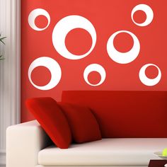 a living room with red walls and white furniture in front of the wall has circles on it