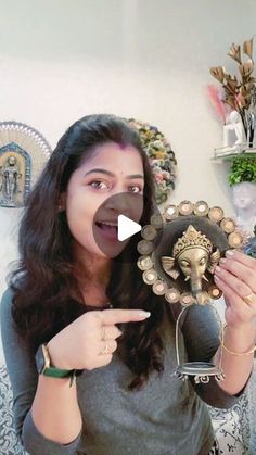 a woman pointing to an elephant head on top of a mirror in her living room