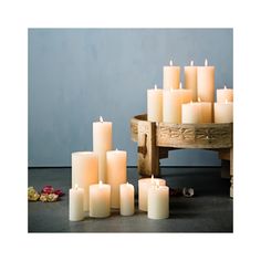 a group of white candles sitting next to each other on a wooden crate with petals scattered around it