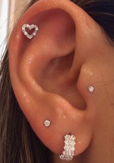 a close up of a person's ear with three piercings