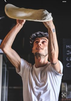 a man holding up a large piece of bread over his head while wearing a white t - shirt